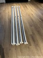 Four white projector screens side by side on wooden floor showing the length and slim design.