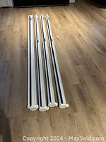 Four white metal casings for projector screens stacked side-by-side on a wooden floor