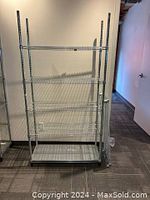 Front view of silver metal wire shelving unit showing five wire shelves and one solid bottom shelf, lightweight frame with capped feet.