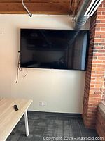 Front view of wall-mounted Vizio television with remote on table below