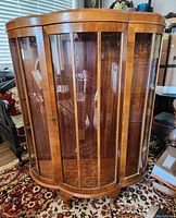Full front view of curved glass and wooden antique china cabinet