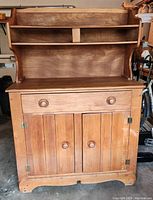 Front view of antique maple sideboard showing drawer, cabinet with double doors, and upper open shelving.