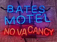 Bates Motel neon sign lit up on tiled floor showing bright blue and red colors.