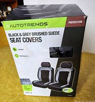 Front of box showing brand Autotrends and seat covers in black and grey brushed suede material