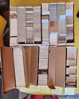 Three long white storage boxes filled with cards sorted in rows, view from above
