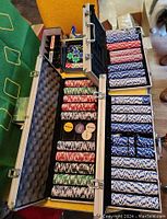 Open case showing organized poker chips and dealer buttons inside, placed next to green blackjack mat