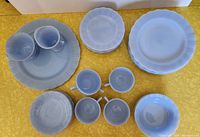 Overview of large plates, small plates, cups, sugar bowl and creamer arranged on table