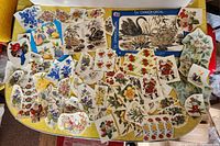 Overview of multiple vintage decal sheets spread on a yellow surface showing swans, flowers, birds, and holiday themes.