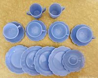 Complete tea set components including four teacups, saucers, plates, one cream and one sugar container, and an extra saucer all arranged on a yellow surface