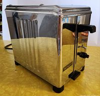 Front angled view showing the polished chrome surface, Toastmaster brand badge, black plastic lever and control knob.