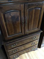 Front view of the wooden bedroom bureau showing two cabinet doors above and two drawers below with decorative metal handles.