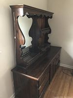 View of full chest of drawers with mirror and shelving, showing dark wood finish and decorative carved details.