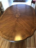 Top view of wooden dining table showing fine wood grain and scalloped edges.