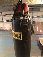 Black leather Everlast punching bag with hanging chains and a pair of red boxing gloves on top.