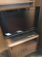 LG 32 inch television on top of the wooden TV stand, showing the front and screen of the TV and the upper compartment of the stand.