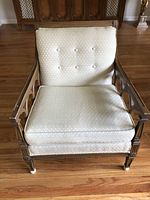 Front view of beige upholstered side chair showing cushioned seat and backrest with wooden frame and carved details.