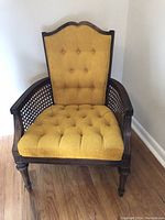 Front view of side chair showing tufted gold fabric upholstery on the seat and back, dark wooden frame, and wicker sides.