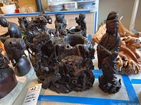 Carved wooden vase and adjacent carved figure with detailed animal and tree motifs.