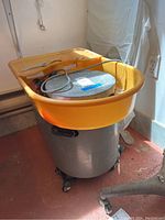 Front view showing yellow splash pan, metal wheel head, and grey base on casters