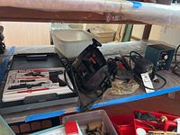 Photo showing Black and Decker tools and Weller soldering gun with accessories on shelf.