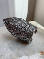Angled view of cuff showing deity motif and floral scroll detail