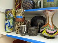 Shelf view showing all seven items: two art glass vases, three ceramic vases and one face planter.