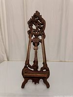 Front view of the carved wooden easel showing detailed scrollwork and ornate design.