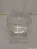 Close-up of etched crystal globe showing continents and meridian lines on clear crystal sphere.