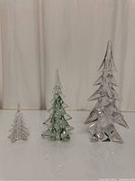 Three glass crystal tree figurines in small, medium with green accents, and large size on white background.