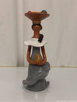 Front view of the terracotta faceless doll showing details of the dress, collar, hat, and small colorful accents.