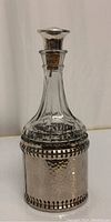 Front view of the crystal decanter with hammered silver-plate casing and cork stopper.