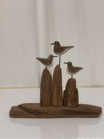 Front view of wooden seagull sculpture showing all three birds and wooden base.