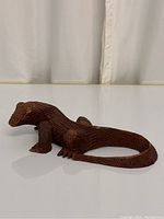 Left side view of the handcarved wooden Komodo dragon sculpture showing detailed scales and claws.