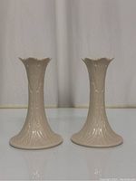 Front view of two Lenox Woodland ceramic candleholders with detailed embossed pattern and ruffled rims.