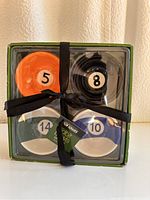 Front view of four pool ball numbered ceramic bowls in packaging tied with a black fabric ribbon showing numbers 5, 8, 10, and 14.