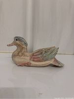 Side view of the pastel colored hand carved wooden duck, showing the full body and detailed wing carving.