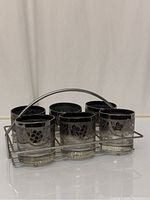 Six mercury fade glasses with silver fruit and leaf pattern arranged in metal wire carrier with handle