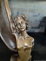 Close-up of the woman’s face and upper torso highlighting facial features and patina details.