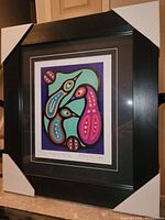 Framed fine art print showing the stylized Thunderbird family artwork with corner protectors on the frame.