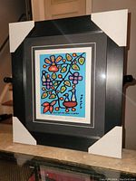 Full view of framed art print with protective corner covers on a surface in indoor lighting.