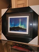 Framed fine art print titled 'Northern Lights' by Tom Thomson, showing the full framed piece with black wide frame and matting. The print features northern lights in blues and greens above a dark landscape.