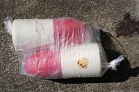 Two plastic crab pot buoys tightly wrapped together in clear plastic, showing primarily white and some red colors.