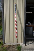 Full view of the rolled American flag with mounting bracket leaning against building wall