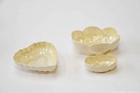 Three yellow ceramic bowls: two shell-shaped, one heart-shaped, shown from the top and side angles.