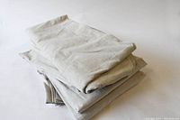 Folded canvas drop cloths stacked on a white background showing fabric texture and general condition.