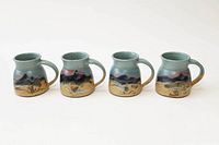 All four small coffee mugs arranged in a row, showing the exterior scenic mountain landscape design with green-blue glaze on top and earthy tones below.