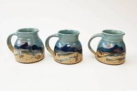 Three large ceramic coffee mugs with blue and brown mountain landscape glaze, signed by Carl Sheehan.