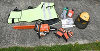 Full layout of chainsaw, chaps, gloves, hard hat with earmuffs and visor, oils, chain file