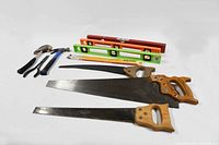 Photo showing 3 handsaws with wooden handles, 3 spirit levels in green, orange and yellow, and part of a claw hammer handle