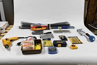 Overview of all tools laid out on a white backdrop showing drill, drill bits, repair kit, staplers, trowels, tape measure, and lock